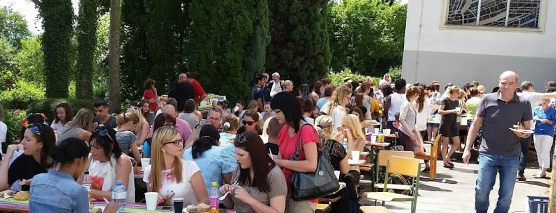 Menschen sitzen auf Bierbänken im Freien und essen und trinken.